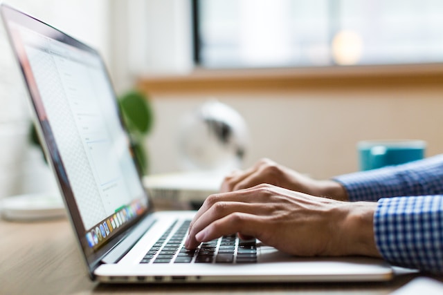 Man typing on a silver MacBook laptop